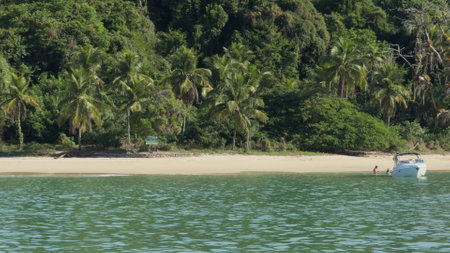 Empty vacation boat on tropical beach shore with lush jungle surroundingsの写真素材