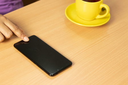 girl hold the phone with coffee and wood table
