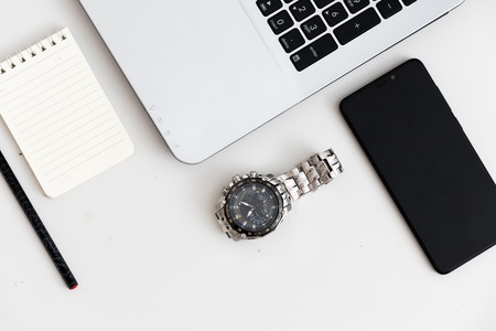 White office desk with laptop, watch, key, office plant, mobile phone. Top view with copy space,...