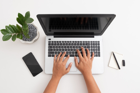 Business woman type on laptop computer on white office desk, coffee, mobile phone , pen, and office plant, Accounting concept with copy spaceの写真素材