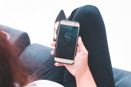 Back view close up of a woman hand using a smart phone with blank screen lying on a couch at home