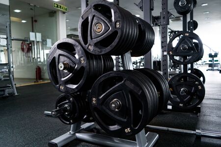 Modern light gym. Sports equipment in gym. Barbells of different weight on rack.の写真素材