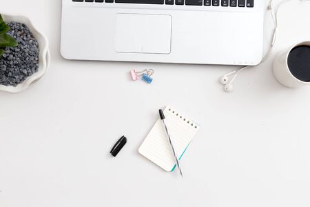 White office desk with notebook and pen and headphone. Top view with copy space, flat lay