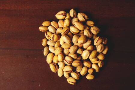 Dried pistachio nuts in class with brown background
