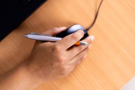 Top view of hands holding mouse on table.の写真素材