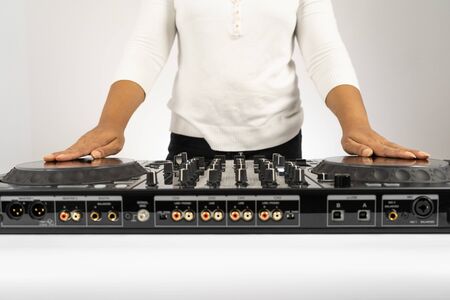 Hands of DJ mixing tracks on professional sound mixer.Fashionable rings on fingers of girl disc jockey playing music.Closeup,knobs and regulators in focus.Girl dj play music tracks at house partyの写真素材