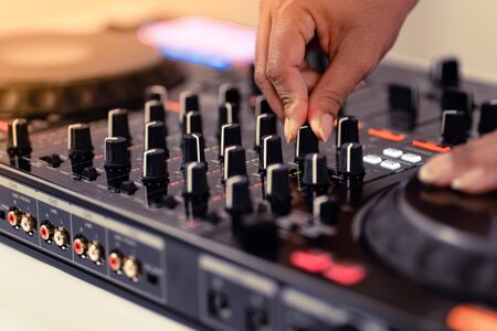 Hands of DJ mixing tracks on professional sound mixer.Fashionable rings on fingers of girl disc...