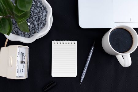 Black office desk with notebook and pen, coffee, laptop, office plant, table watch. Top view with copy space, flat layの写真素材