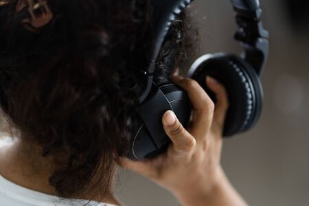 Close-up portrait of young beautiful brunette woman listening to music and holding white headphonesの写真素材