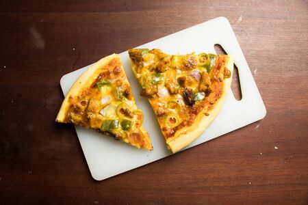 Pan Pizza slice on tray with dark brown wood top closeupの写真素材