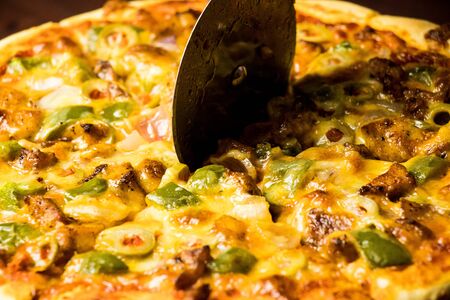Pan Pizza cutting side closeup with dark brown woodの写真素材