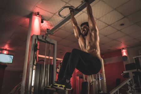 Strong man doing pull ups in gym