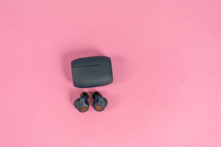Wireless headphones on pink table with background
