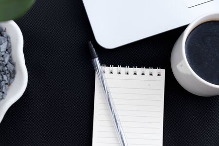 Black office desk with notebook and pen, coffee. Top view with copy space, flat layの写真素材