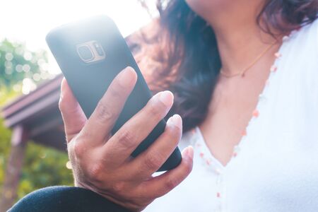 Back view close up of a woman hand using a smart phone with blank screen outsideの写真素材