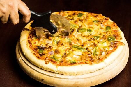 Pan Pizza cutting side closeup with dark brown woodの写真素材