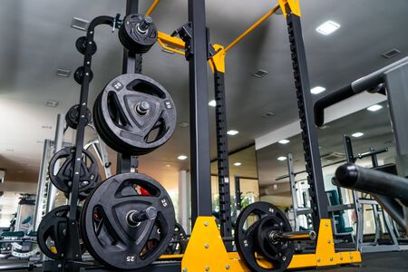Modern light gym. Sports equipment in gym. Barbells of different weight on rack.