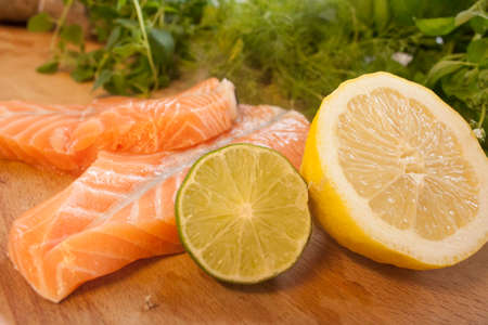 Salmon and sitrus fruits on a wooden cutting boardの写真素材