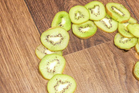 Green kiwi slices, on brown, wooden backgroundの写真素材