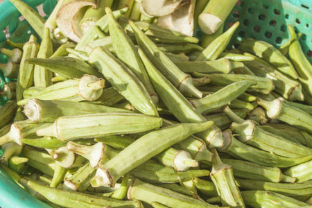 A pile of green okra in a basket, at a market