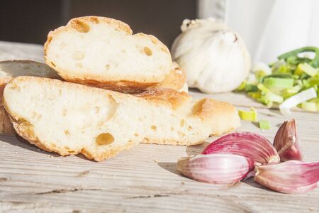 A pile of garlic bread, in front of garlic and leekの写真素材