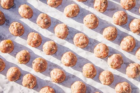 A plate full of pink, raw meatballsの写真素材