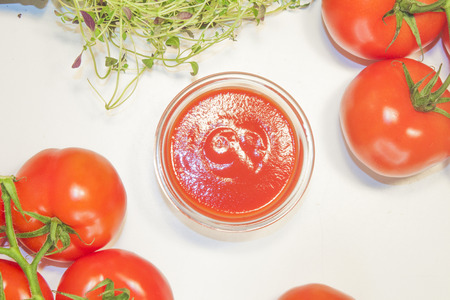Tomato sauce on a white table, between tomato and herbsの写真素材