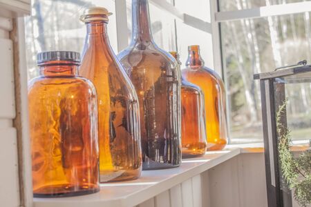 A few brown glass bottles, in front of a windowの写真素材