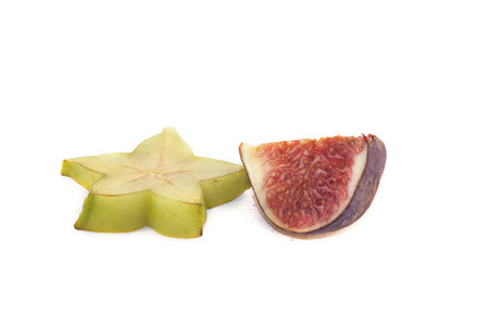 A green carambola and a purple fig, on white backgroundの写真素材