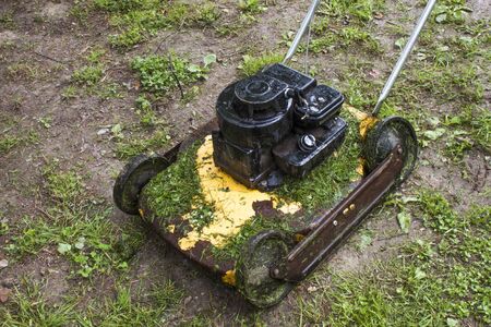 Old yellow, grass cutter, and a lot of fresh cutted grassの写真素材