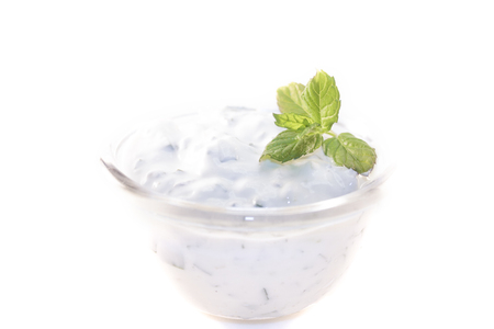 A glass bowl full of garlic, mint, cucumber tzatziki yoghurt sauce, isolated on white backgroundの写真素材