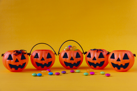 Halloween Jack o Lantern bucket filled with candies on yellow backgroundの写真素材