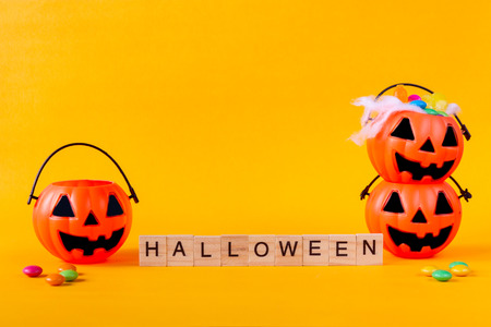 Halloween Jack o Lantern bucket with candies and Halloween word on yellow backgroundの写真素材