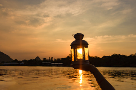 lamp on hand in sunbeam over sunset. power and idea concept