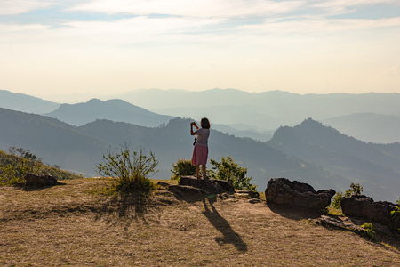 Asian tourist  taking photo from top of the mountain with valley view of Doi Pha Tang Chiang Rai.の写真素材