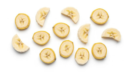 Sliced bananas arranged on a white background, showcasing their yellow color and star-shaped centers.の素材