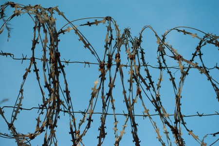 Old rusty barbed wire fencing against the blue sky