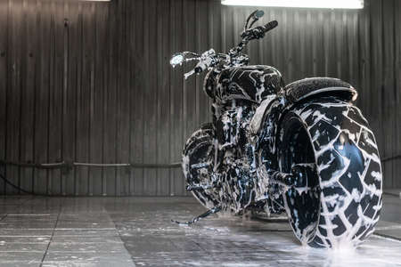 Black motorbike in soap foam at the car washの写真素材