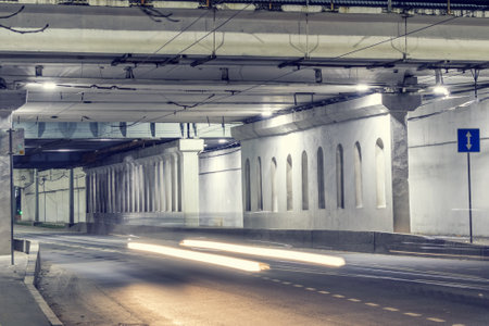 Night city street under the bridge, road with a reverse motion with an information signの写真素材