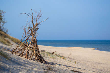 sandy beach of a sea and tipie made of the wood thrown on the seashore in the national park Curonian Spitの写真素材