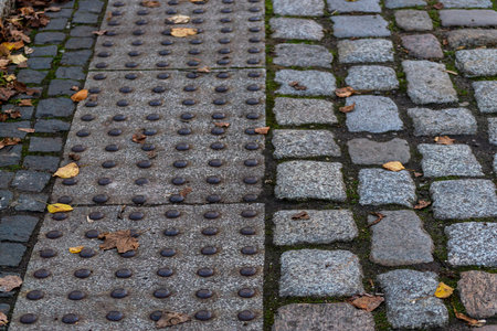 tactile tiles for the visually impaired combined with textured paving with traditional cobblestonesの写真素材