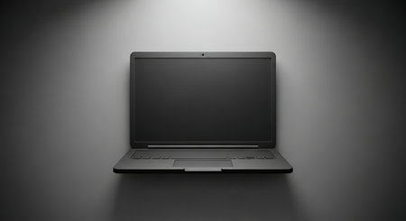 A dark laptop sits on a shelf, illuminated by a spotlight from above, creating a stark contrast and a minimalist, modern aesthetic. The image emphasizes technology and design.の素材