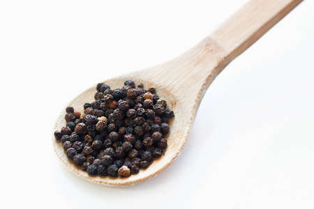Black peppercorns in wooden spoonの写真素材