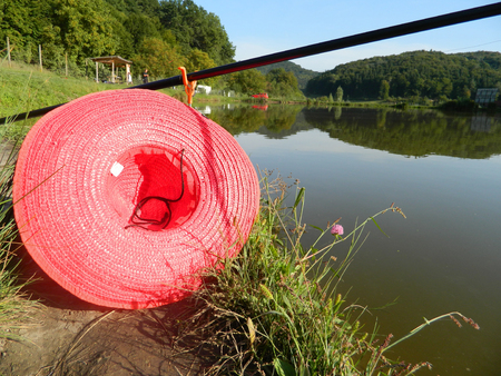Fishing poles lauched into lake with red had near.の写真素材