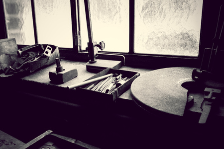 old workshop with workplace in an old factory with gloomy admosphere and window in background in black and whiteの写真素材