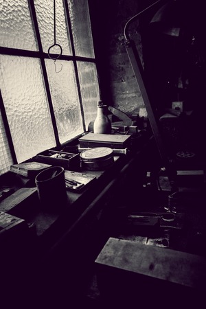 old workshop with workplace in an old factory with dark touch and window in background in black and whiteの写真素材