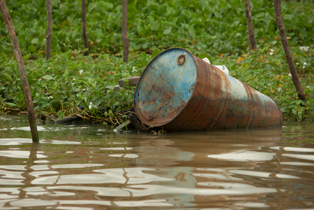 environmental damage and oil barrel near a floating village on the tonle sap close to siem reap in cambodiaの写真素材
