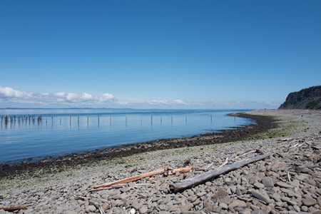 Sea and stony beach in front of Dark harbour on Grand Manan New Brunswick Canada with fishing equipment and blue skyの写真素材