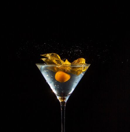 A Peruvian ground cherry, also called physalis, in an illuminated cocktail glassの写真素材