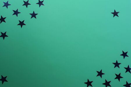 Star shaped confetti on a green background. Festive background. Holiday concept. Top view, flat...